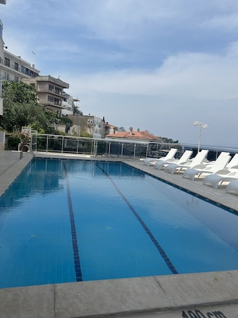 Una piscina al aire libre, sombrillas, sillones reclinables de piscina