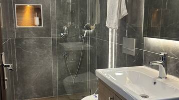 A modern bathroom with a glass-enclosed shower, a white sink, and a wooden vanity.