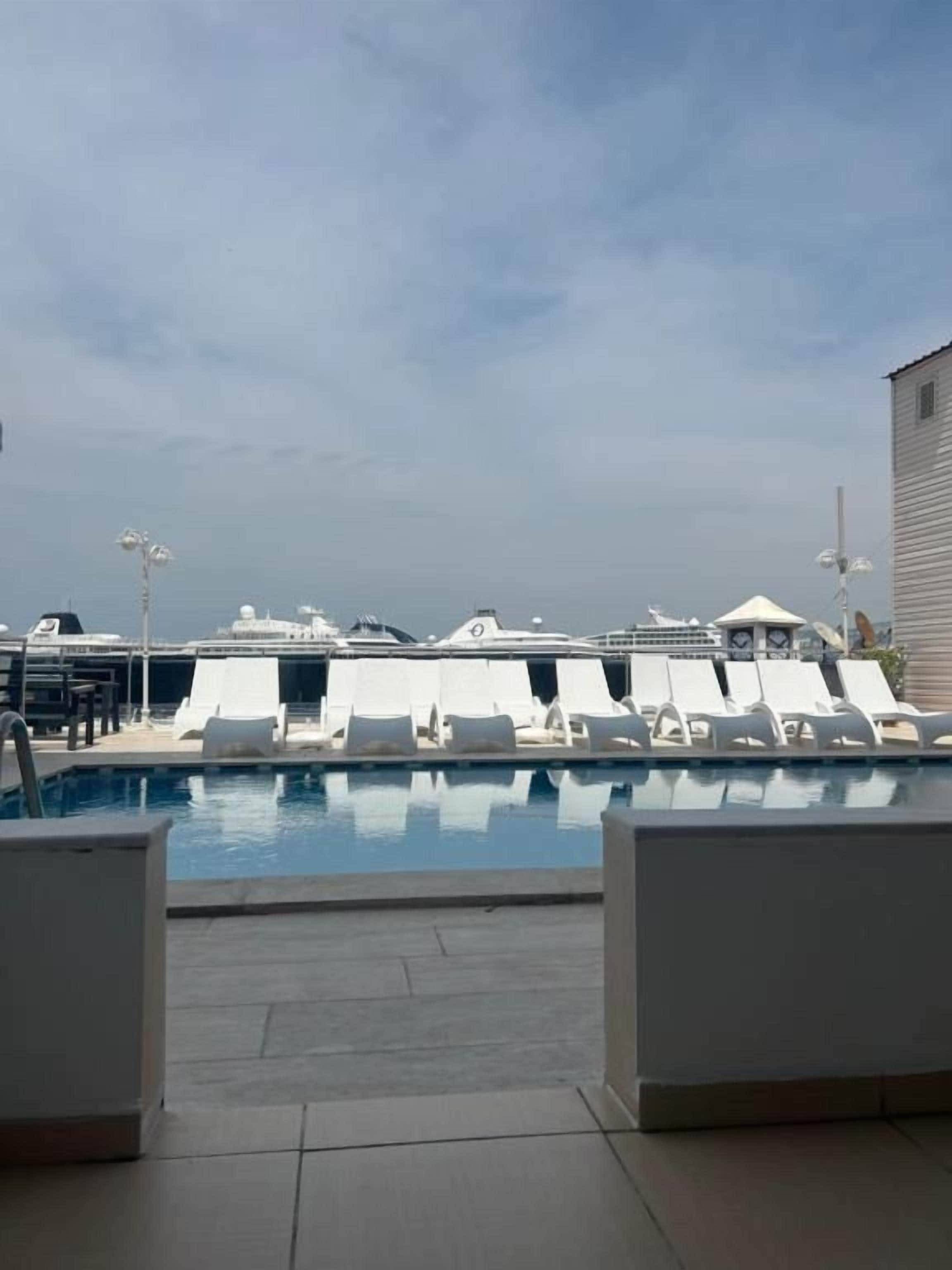 Un área de piscina con sillas de descanso y un edificio al fondo.