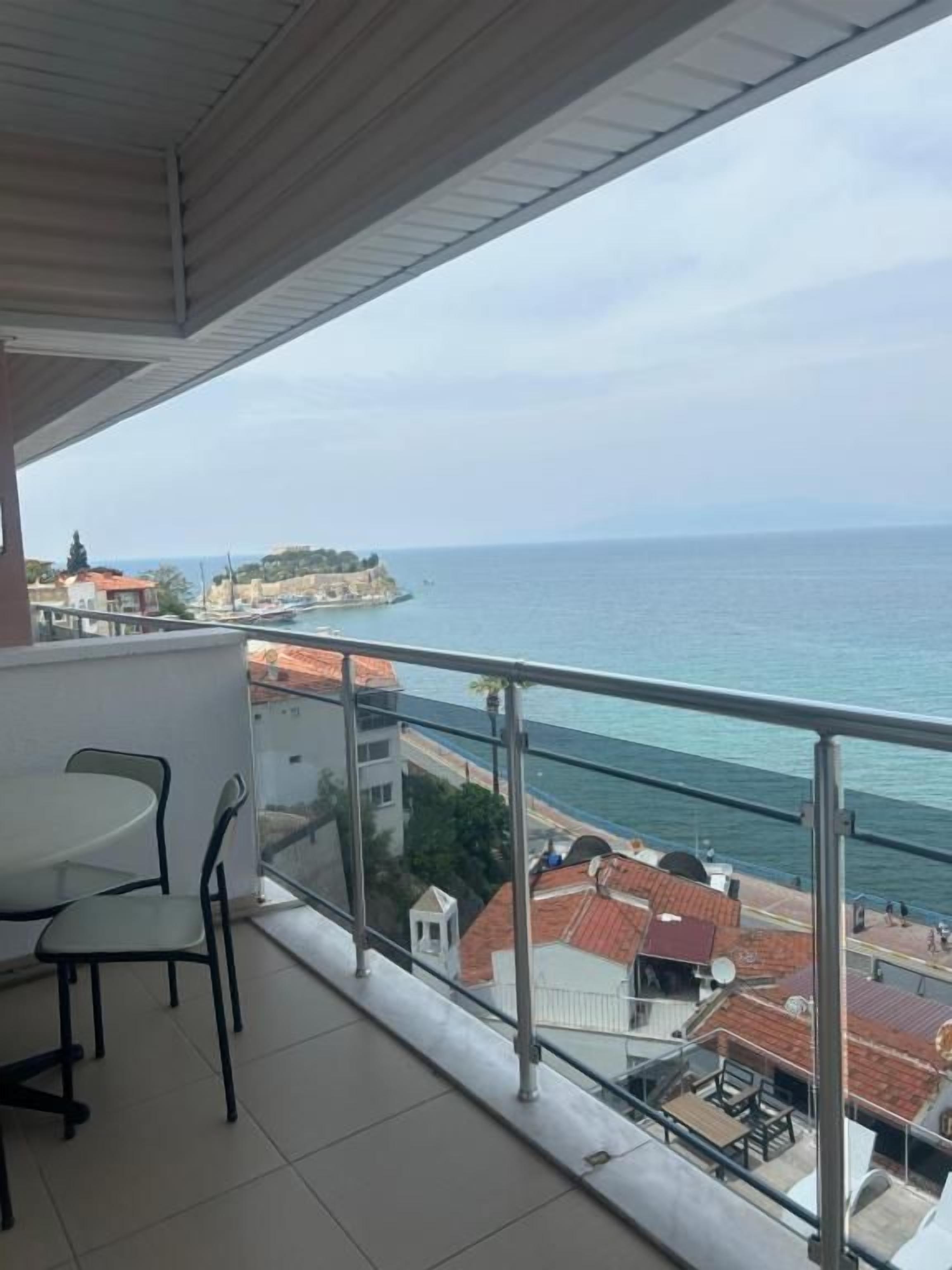 A balcony with a view of the sea and a distant island.