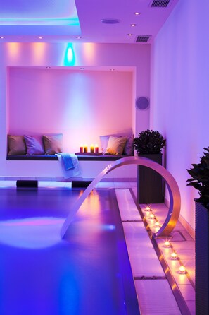 Un área de spa moderna con zona de estar, velas y fuente de agua.