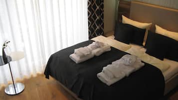 Ein Hotelzimmer mit einem ordentlich bezogenen Bett, einem Nachttisch mit Lampe und einem Fenster mit Jalousien.