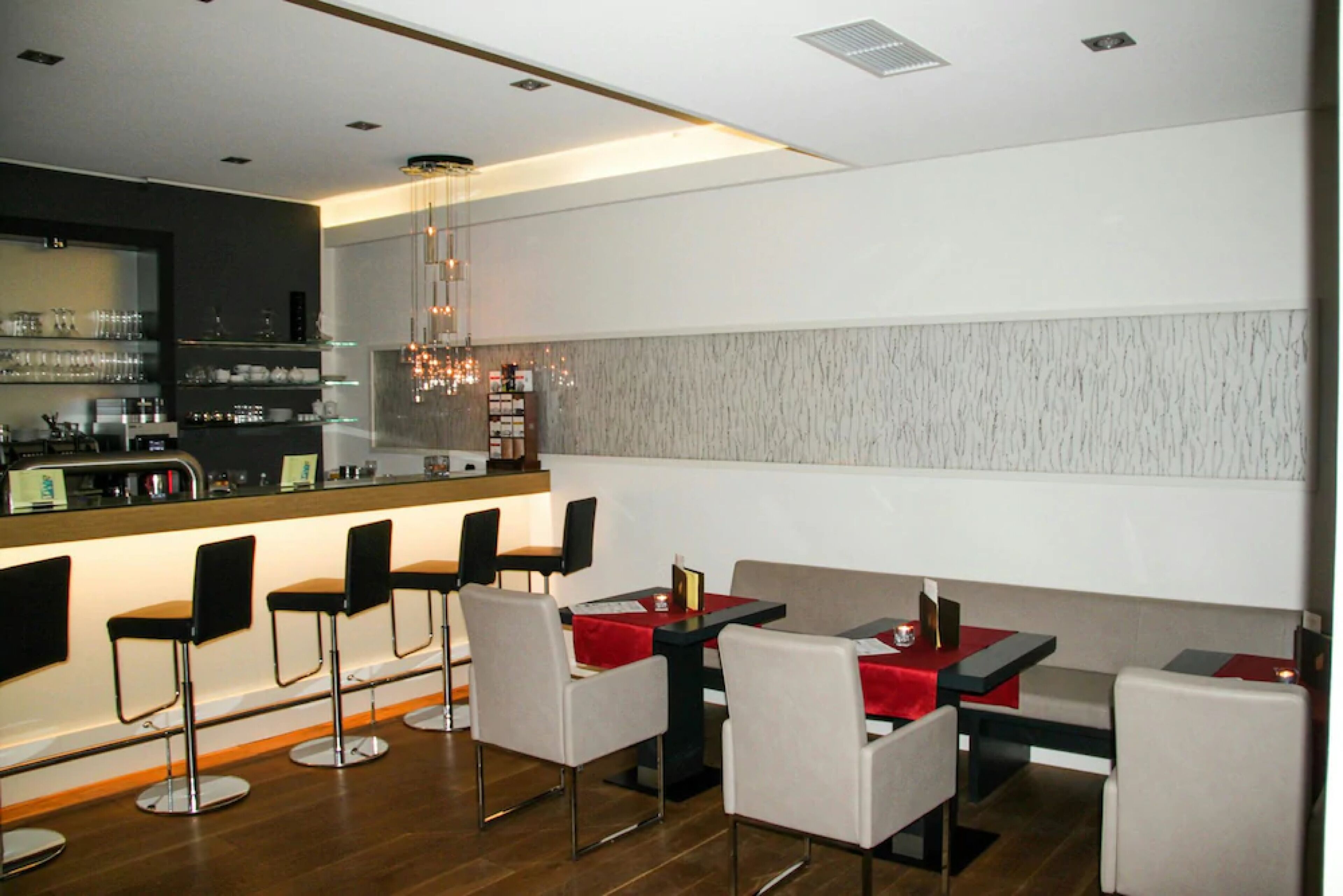Ein modernes Restaurant mit Barhockern, hohen Tischen und einer Theke.