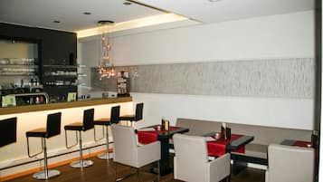 Et moderne restaurantmiljø med barpladser, høje borde og en bardisk.