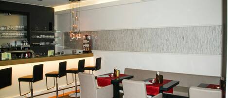 A modern restaurant interior with bar seating, high tables, and a bar counter.