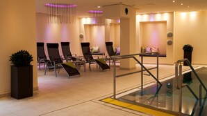 Un área interior moderna para relajarse, con asientos, barandilla de cristal e iluminación ambiental.