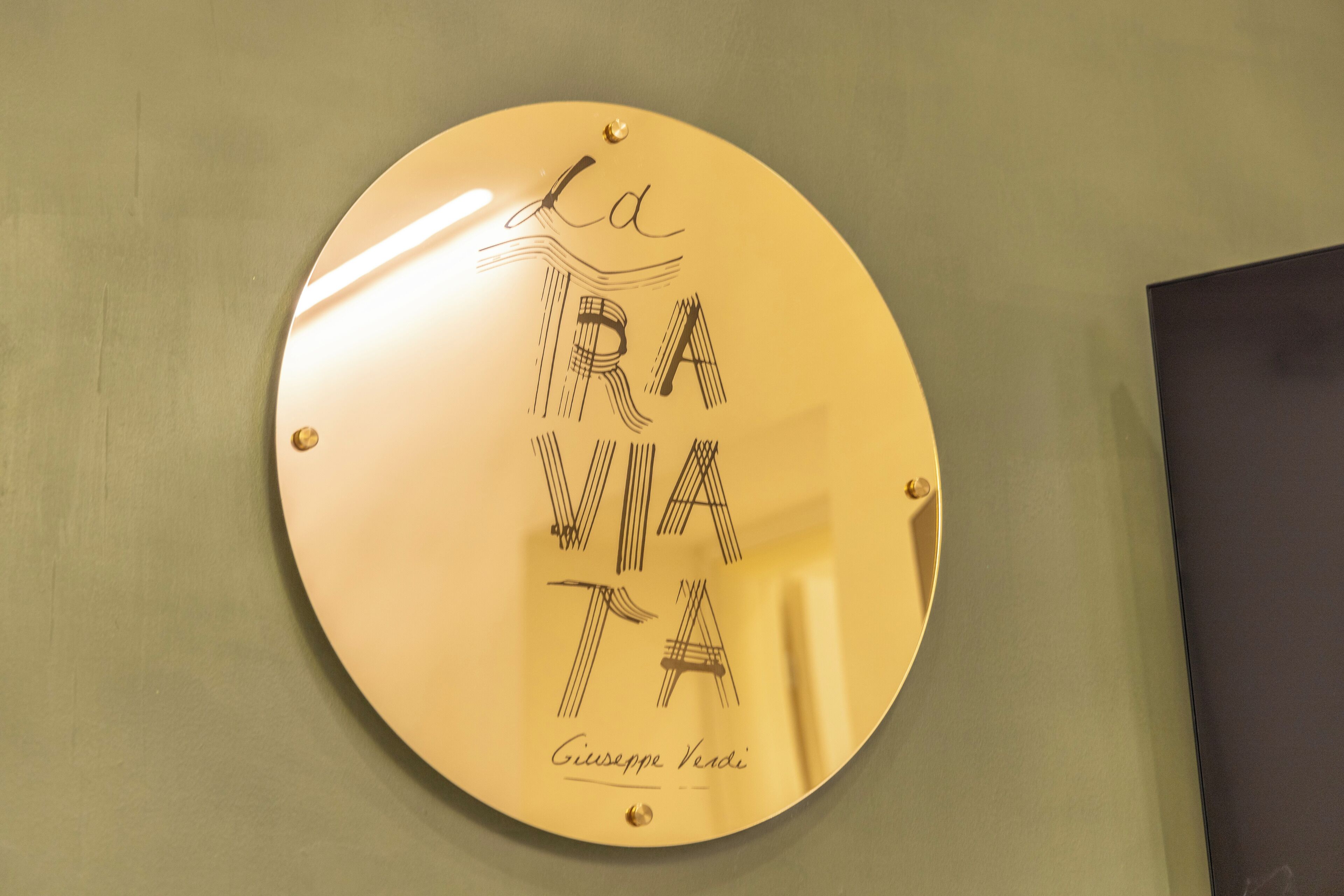 A circular sign with the text "La VIA Giuseppe Verdi" mounted on a wall.