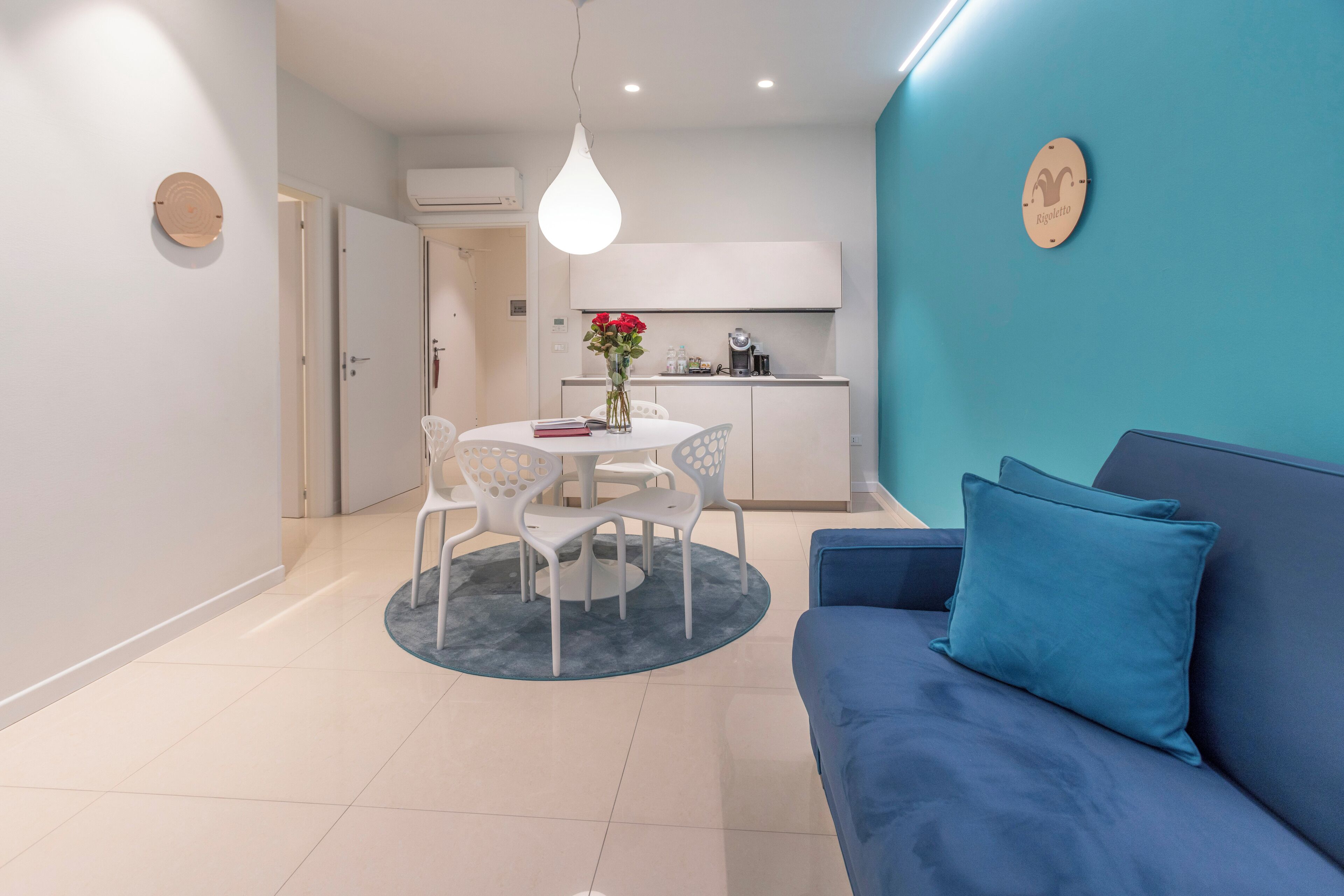 A modern living room with a blue sofa and a round table with chairs.