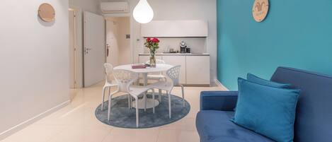 A modern living room with a blue sofa and a round table with chairs.