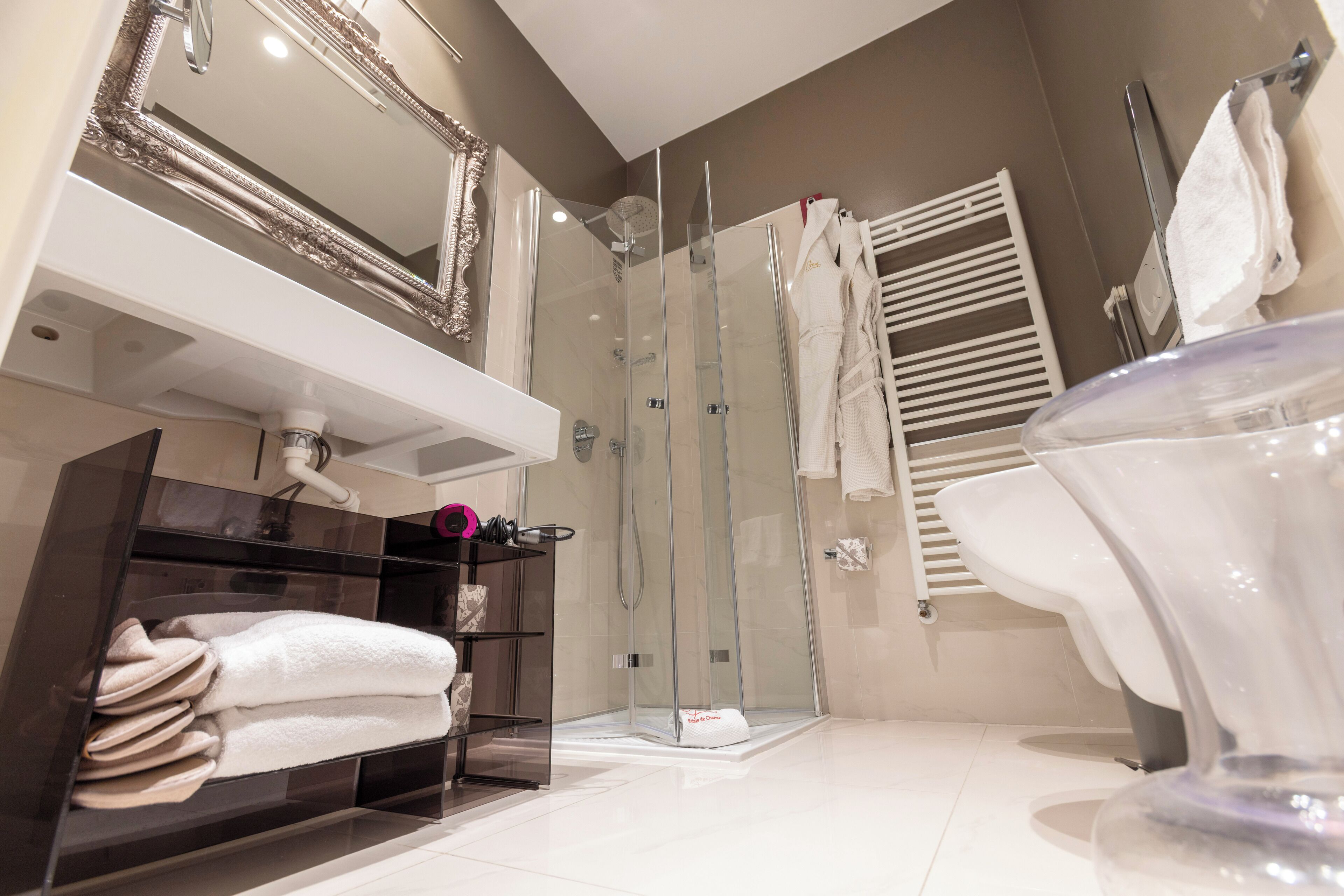 Ein modernes Badezimmer mit einer gläsernen Duschkabine, einem weißen Waschbecken mit Spiegel darüber und einer Badewanne aus Glas.