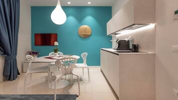 Una cocina moderna con una pared de acento color aguamarina, un plato decorativo redondo y una zona de comedor con sillas blancas y una mesa.