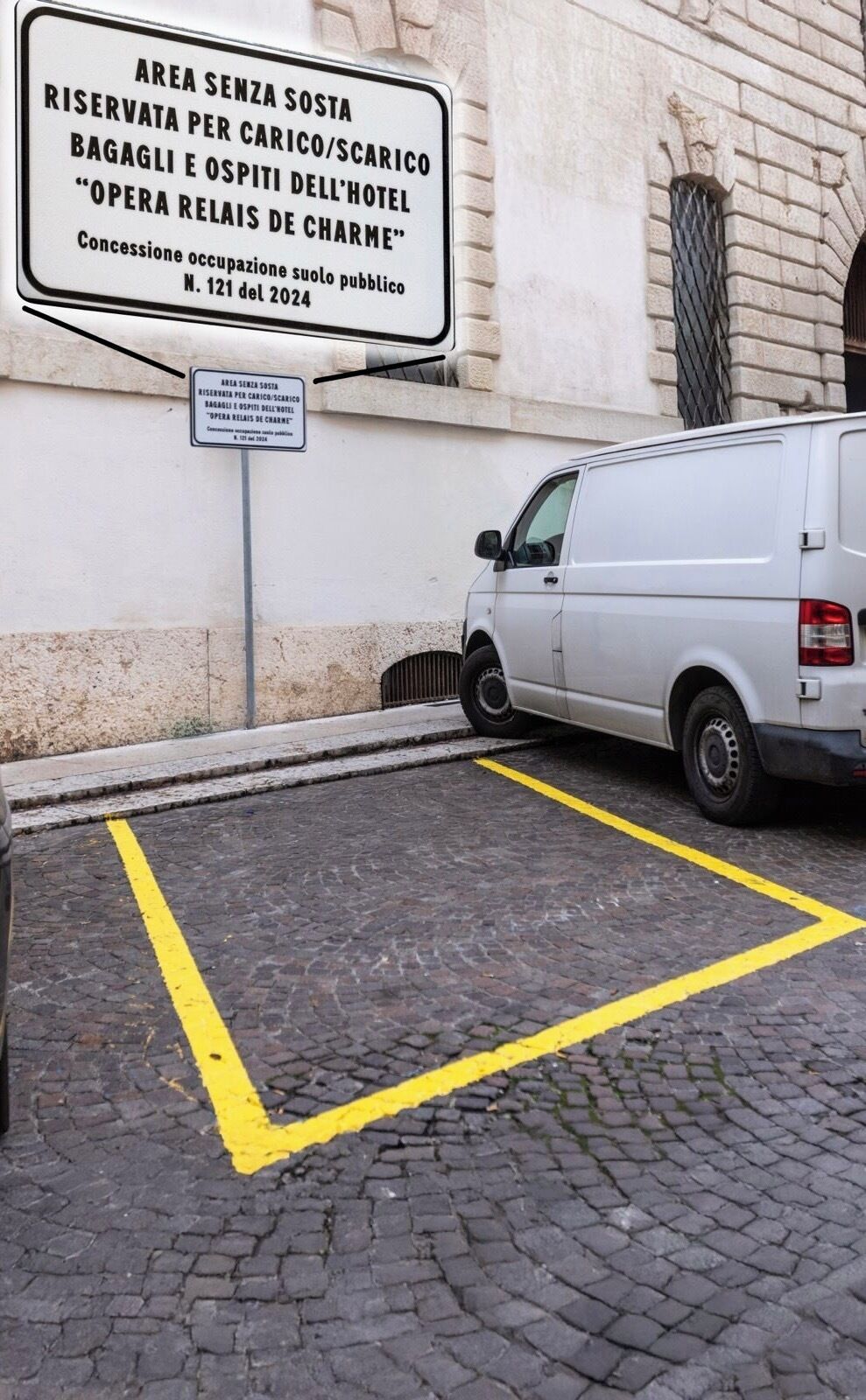 A parking area with a white van parked next to a building with a sign indicating it is reserved for hotel guests and staff.