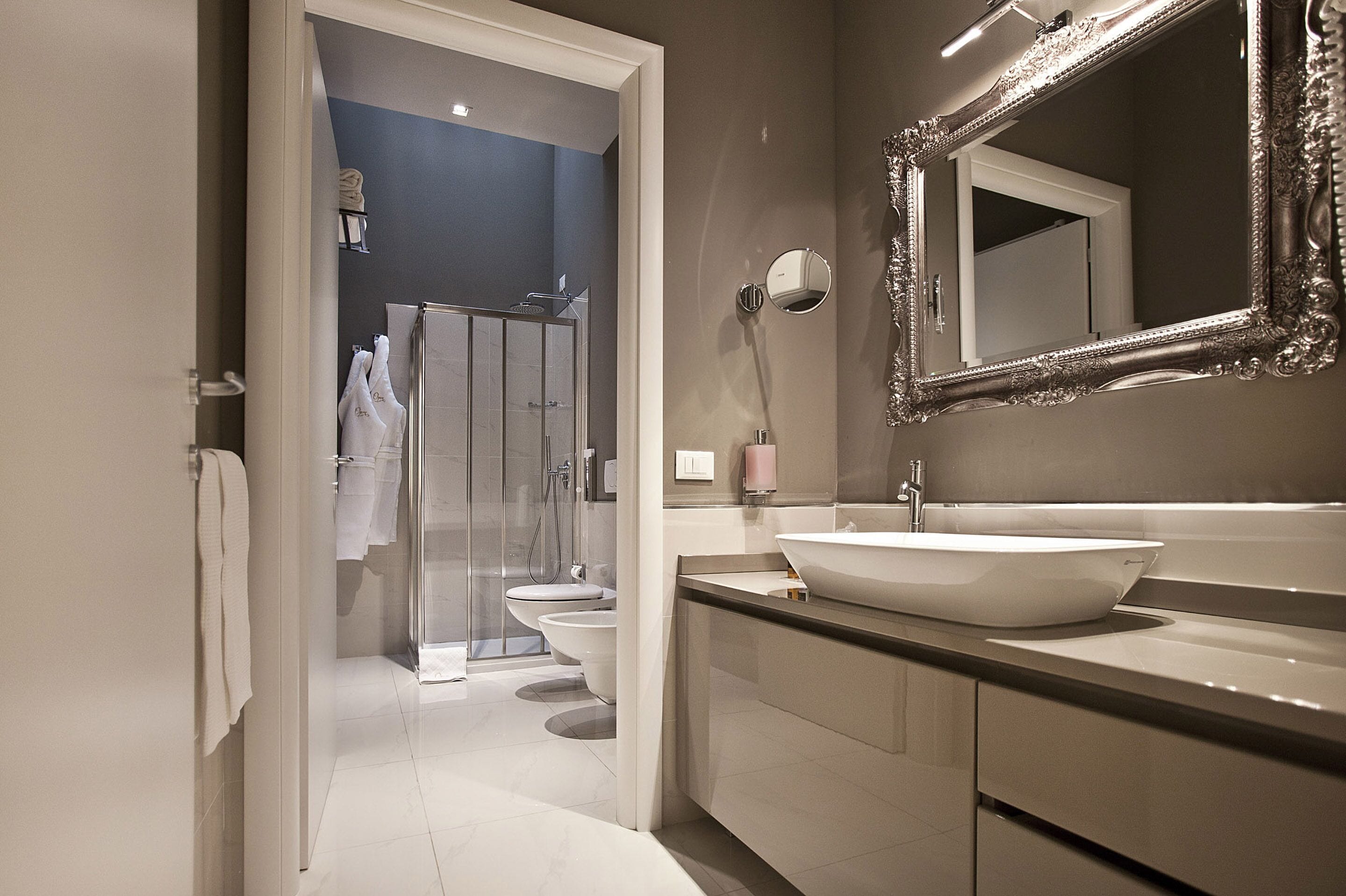 Une salle de bain moderne avec un grand miroir, un lavabo blanc et une cabine de douche en verre.