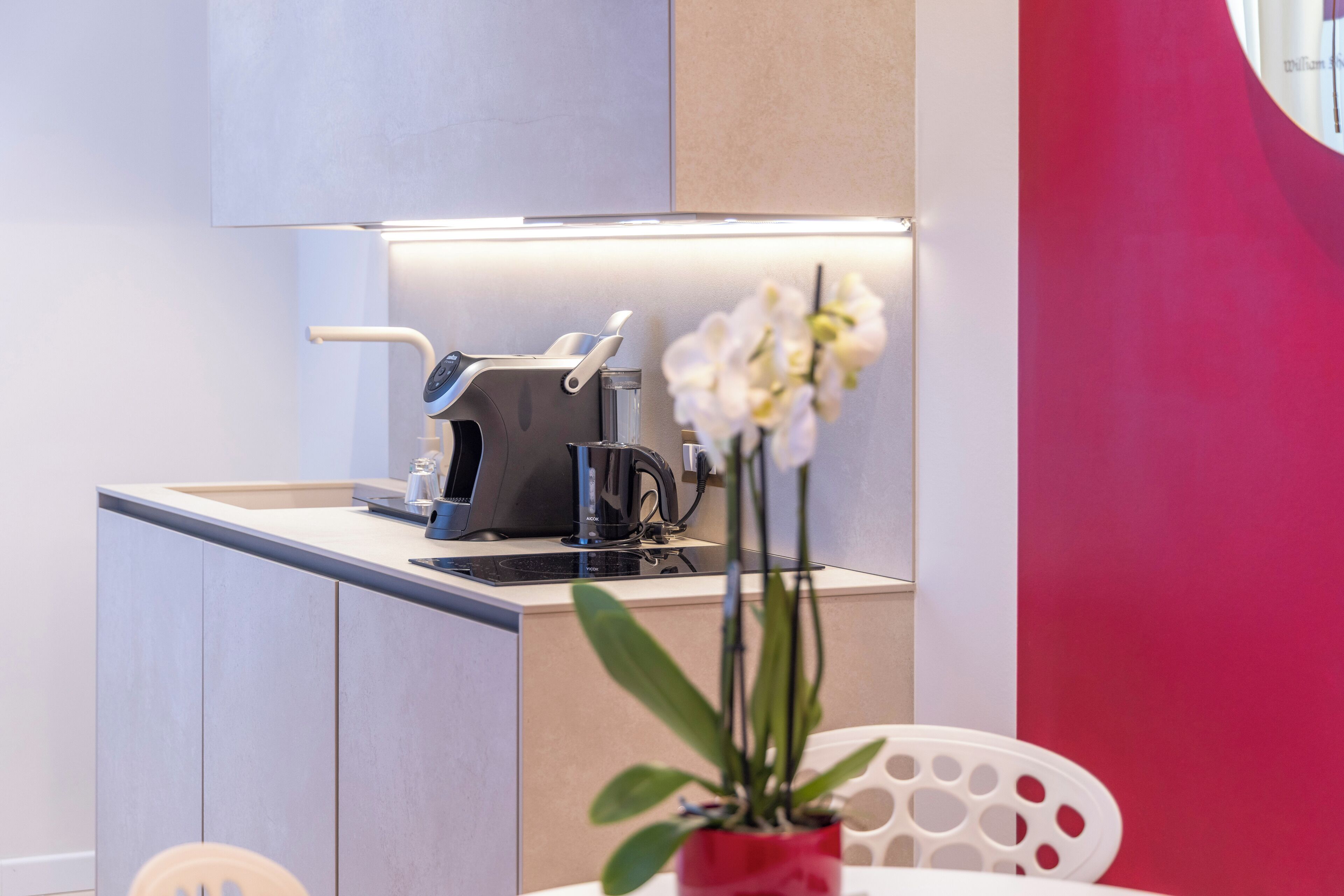 A compact kitchenette with a coffee maker, a kettle, and a small sink.