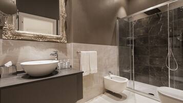A modern bathroom with a large mirror, a vessel sink, a bidet, and a glass-enclosed shower.