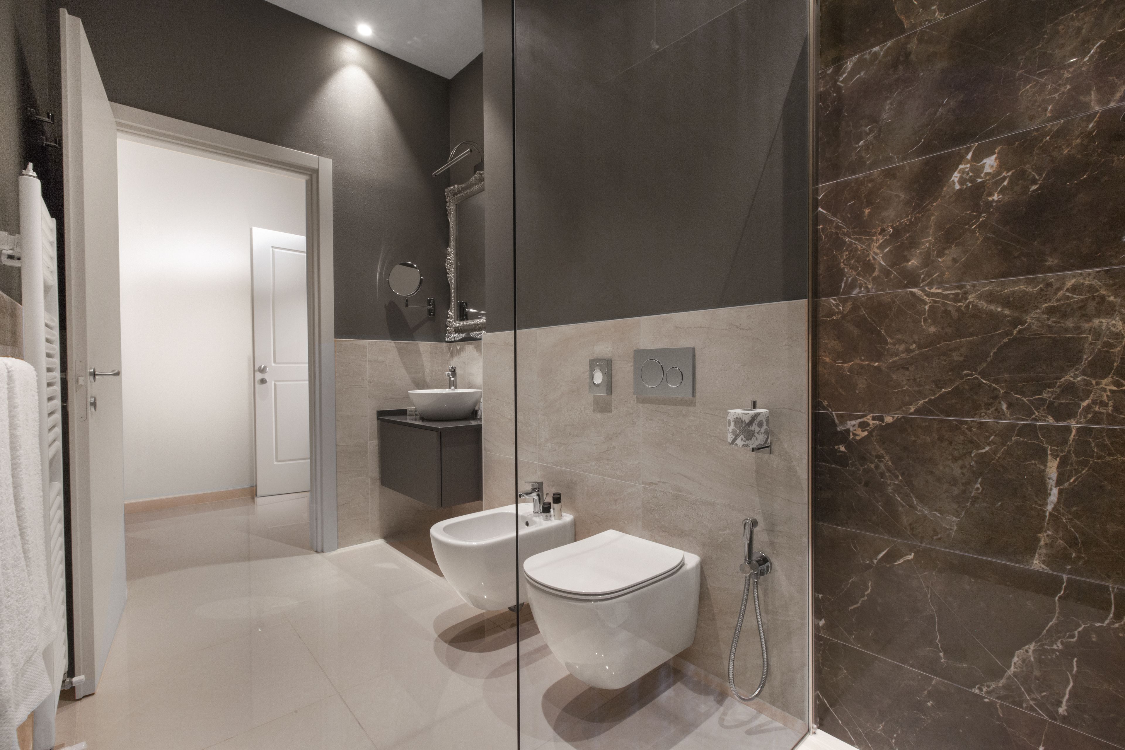 Un baño moderno con bidé, inodoro y zona de ducha con mampara de vidrio.