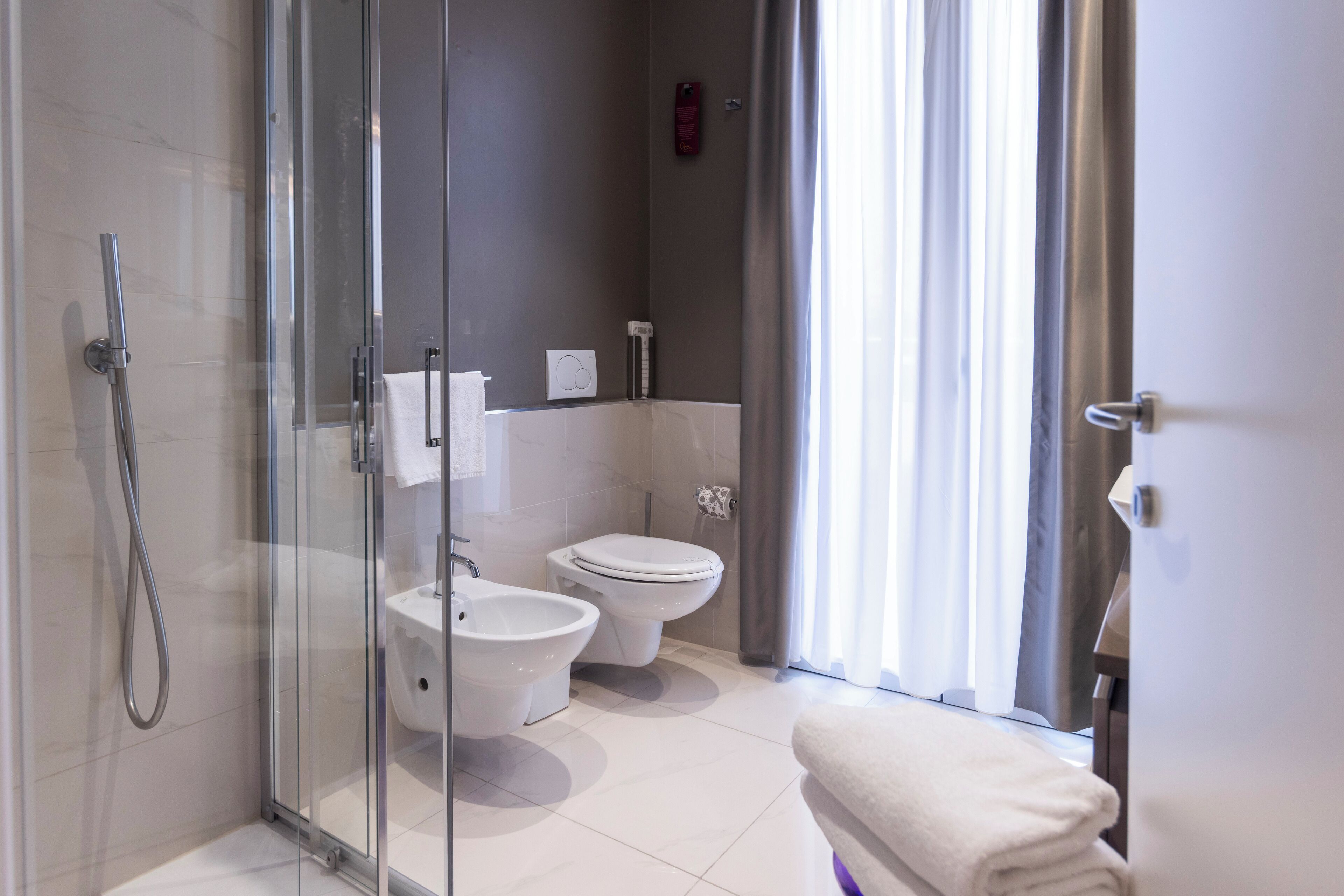 Une salle de bain moderne avec une douche à parois de verre, un bidet, des toilettes et un porte-serviettes.