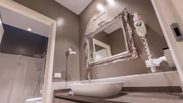 Un baño moderno con un espejo grande, un lavabo blanco y un secador de pelo en la pared.