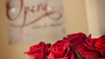 A framed sign with the word "Opera" and a bouquet of red roses in front of it.