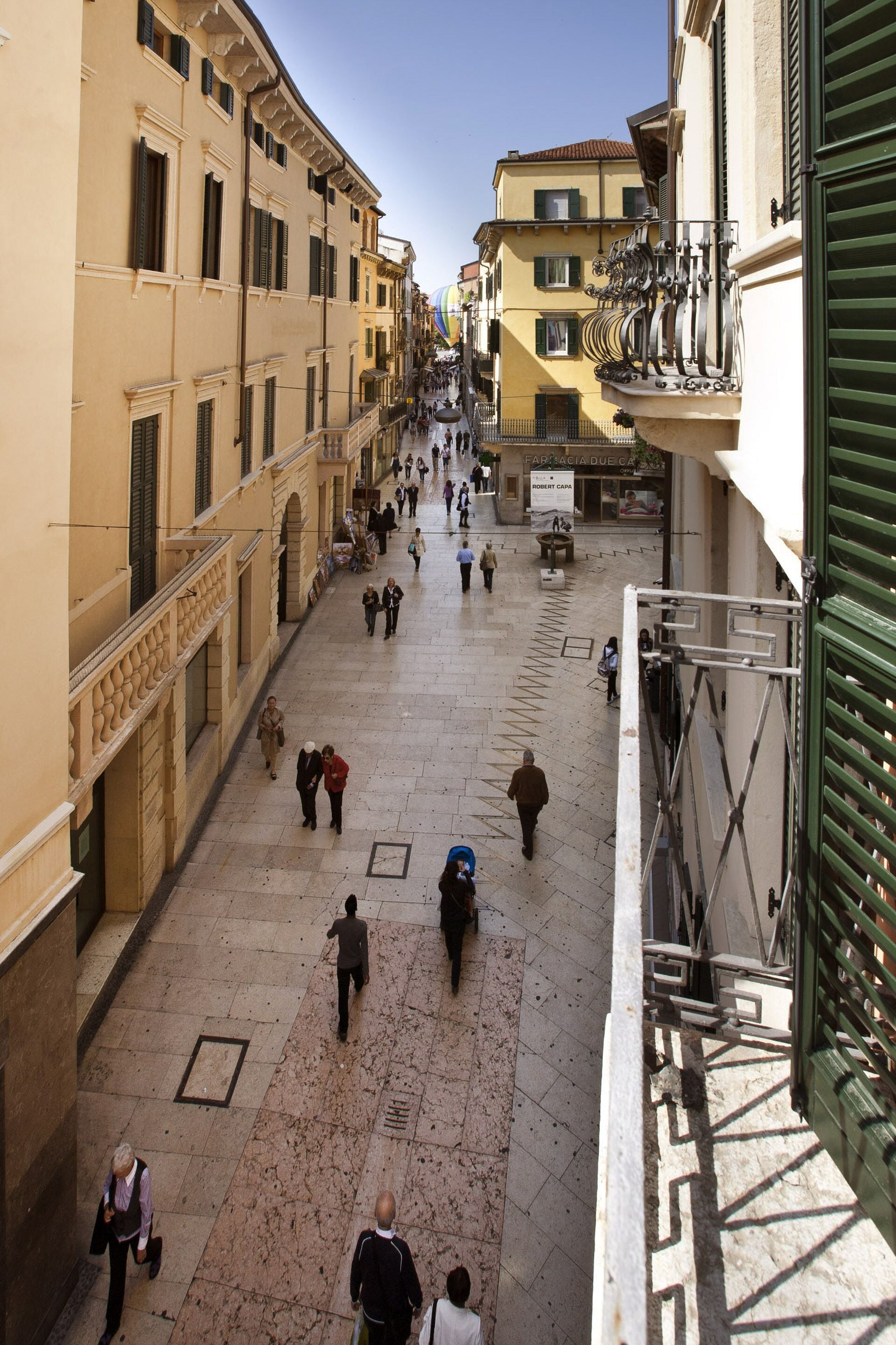 A wide, open public square with historical buildings on either side, featuring a mix of architectural styles and a clear sky above.