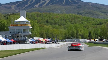 Una pista di gara con un'auto in movimento, circondata da tende e una torre di controllo.