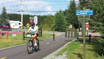Un ciclista en un camino pavimentado con señales direccionales hacia 'Hôtel Vacances Tremblant' y 'Secteur Centre-Ville'.