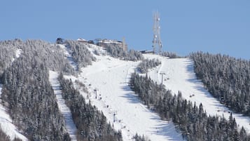 A snow-covered ski slope with ski lifts and buildings in the background.