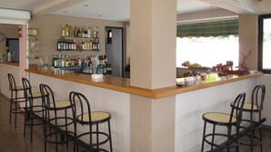 A bar area with a counter, multiple chairs, and shelves stocked with bottles. - Karina (Corfu)