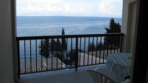 A balcony with a view of the sea, a table with a checkered tablecloth, and a chair. - Karina (Corfu)