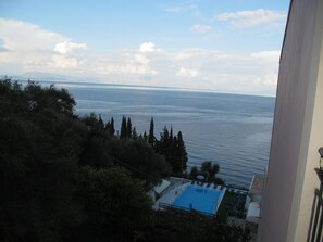 A view of a pool area with a clear sky and distant mountains. - Karina (Corfu)