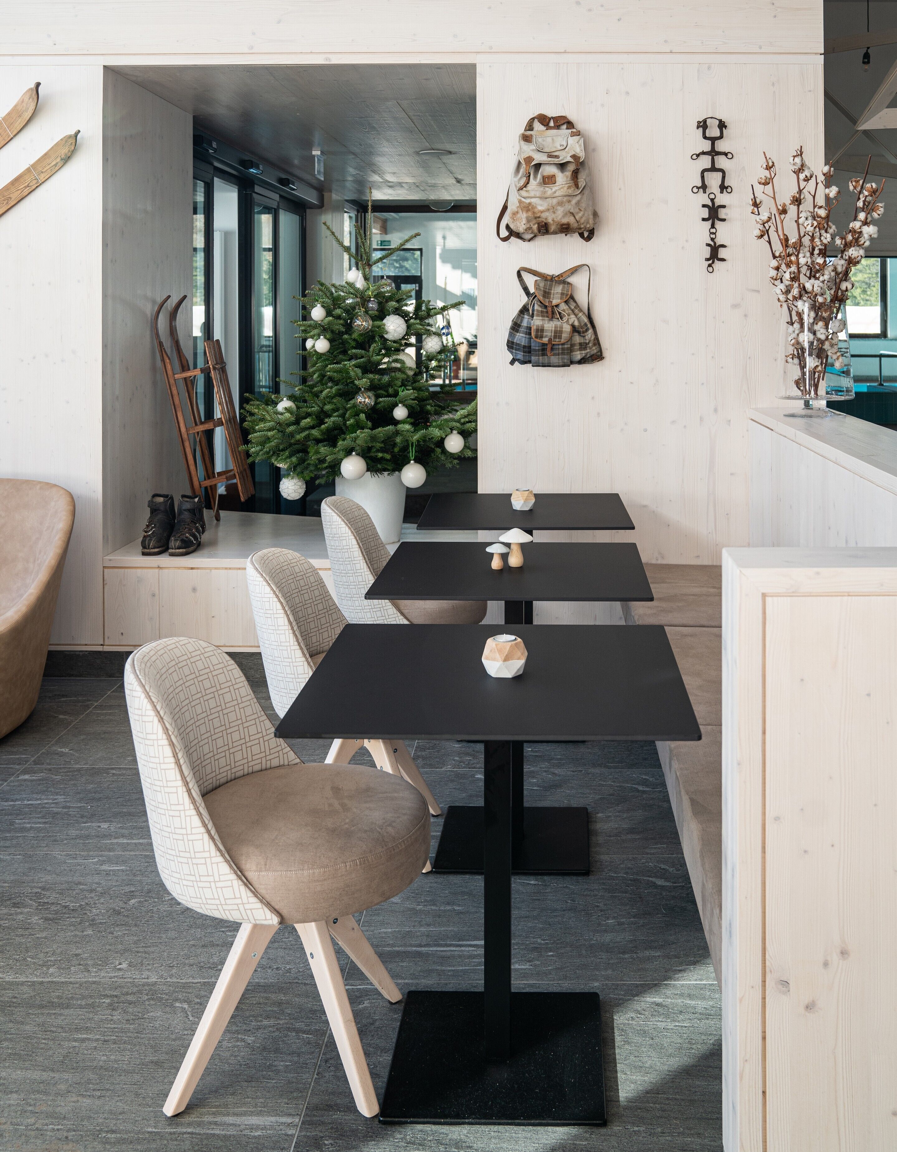 A modern dining area with a central table, four chairs, a Christmas tree, and wall decorations.