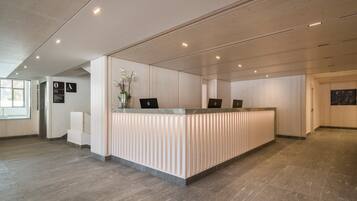A modern reception desk with two laptops, a vase with flowers, and a sign with letters 'A' and 'O'.