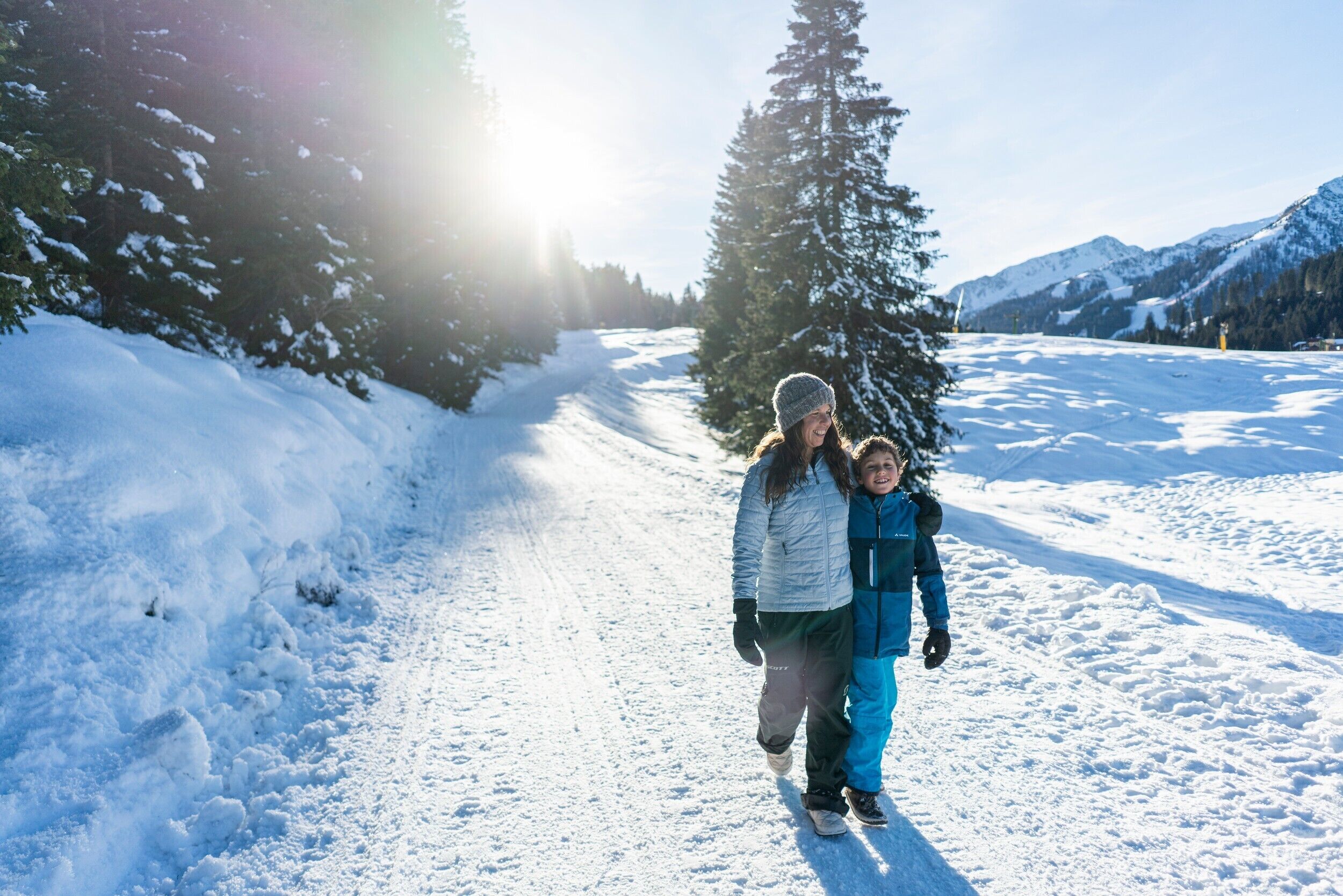 A snowy path with a person and a child walking.