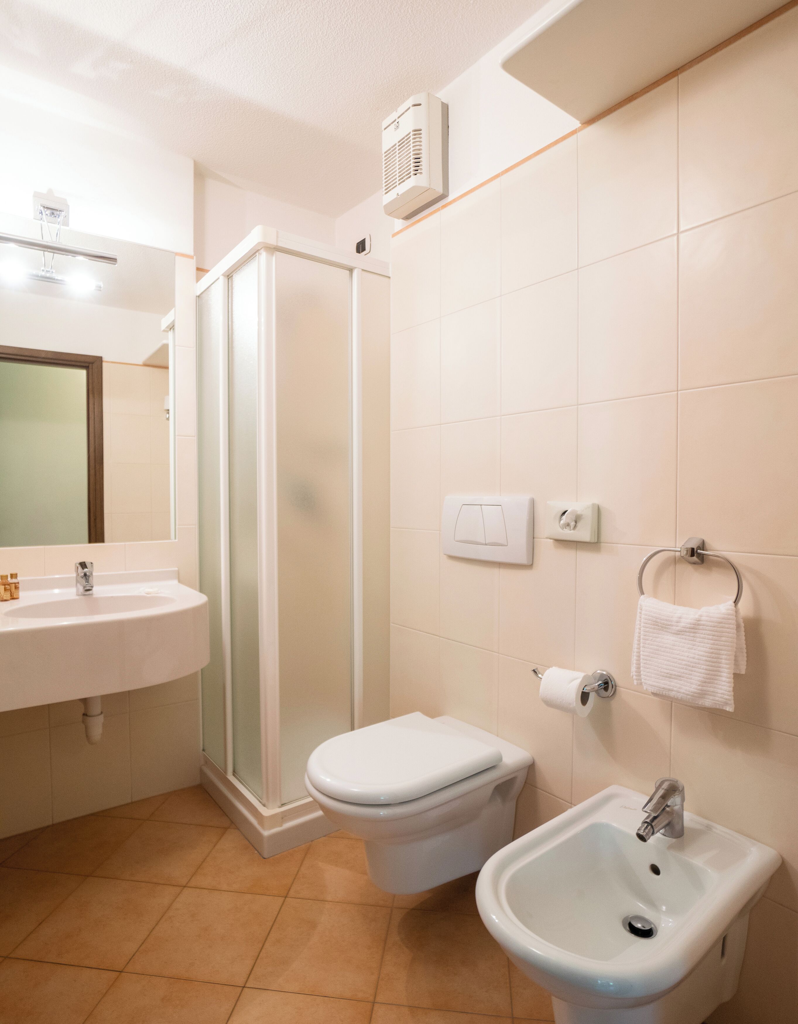 A bathroom with a shower, toilet, sink, and towel rack.