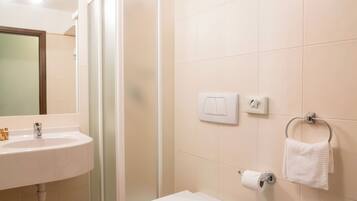 A bathroom with a shower, toilet, sink, and towel rack.