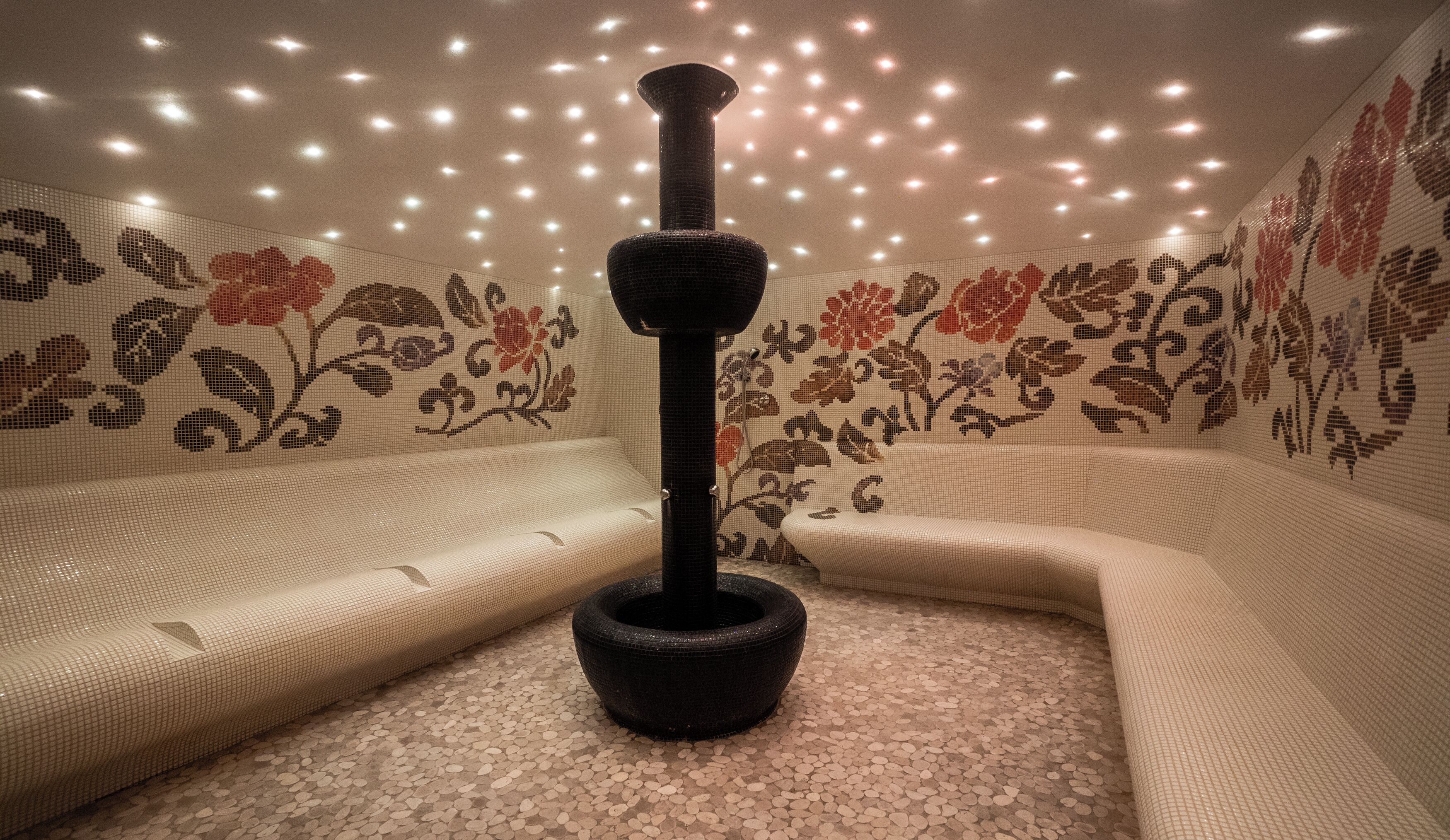 A room with a textured floor, a central pillar, and walls with floral patterns.
