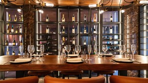 Eine Bar mit einer langen Holztisch, mehreren Flaschenregalen und orangefarbenen Stühlen.