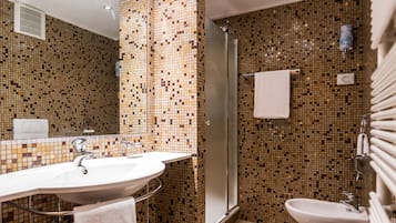 Ein Badezimmer mit Waschbecken, Toilette und Dusche. Die Wände sind mit einem Mosaikmuster gefliest.