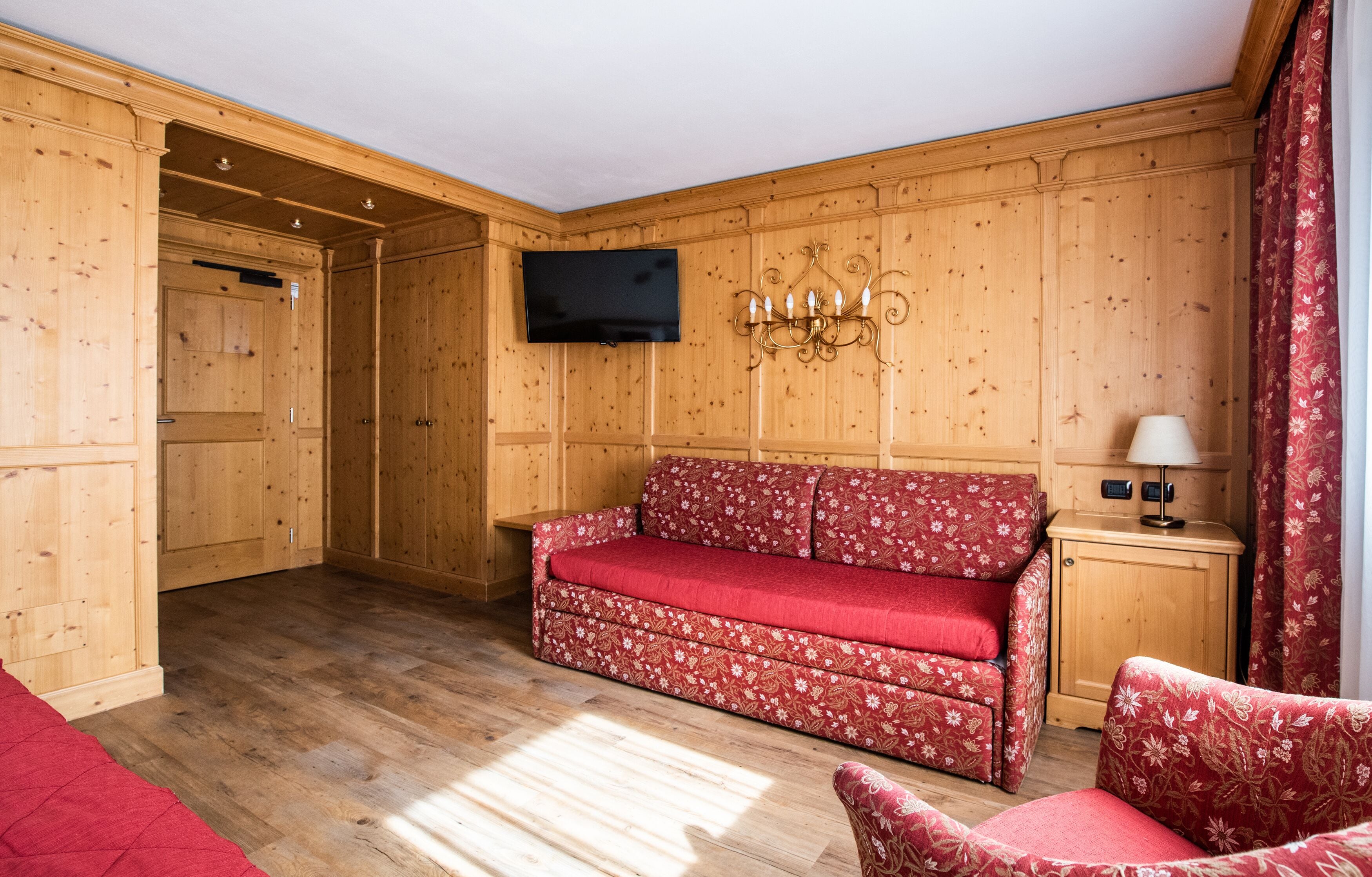 Una habitación con paneles de madera, un sofá, un televisor y una lámpara.