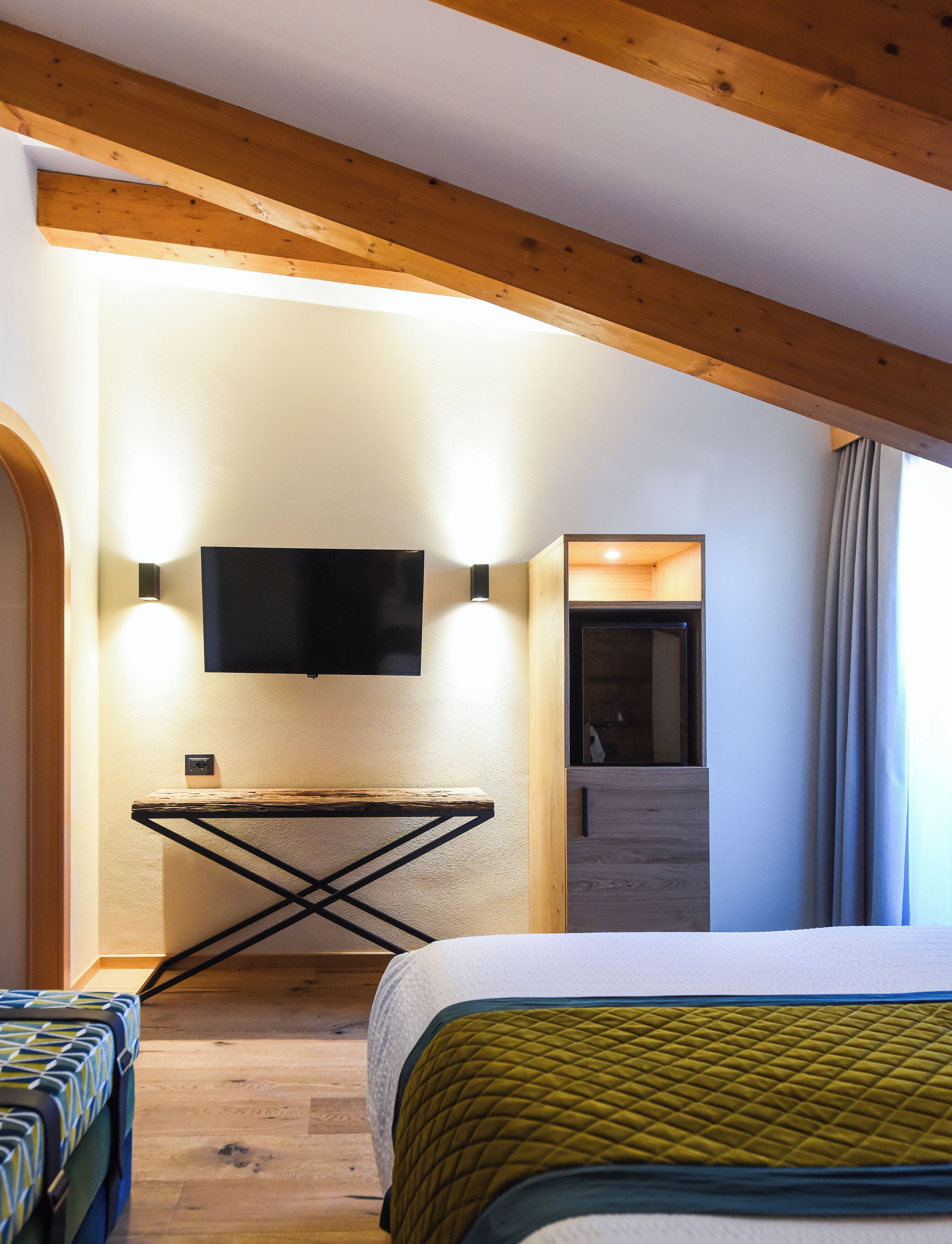 Une chambre moderne avec un lit, un téléviseur fixé au mur et un plafond en bois.