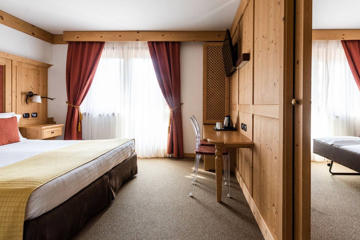 Habitación de hotel con dos camas, paredes de madera, un escritorio y una silla.