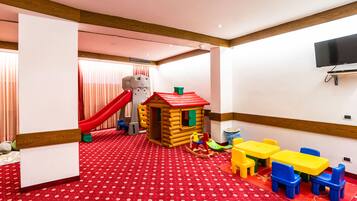 Un'area giochi per bambini con uno scivolo, una casetta e mobili colorati.