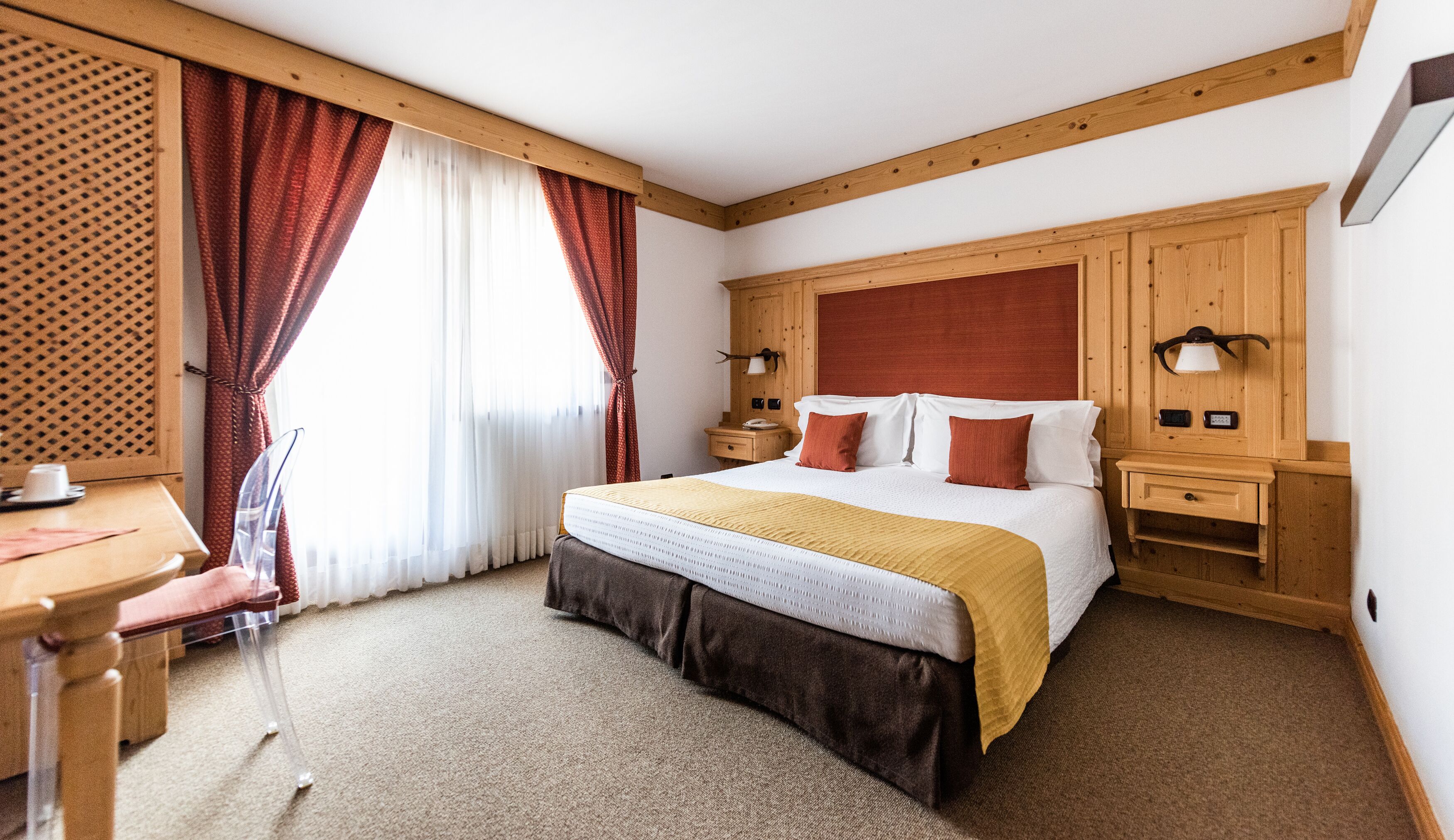 Een hotelkamer met een bed, een bureau, een stoel en een raam met gordijnen.