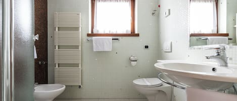 Un baño con inodoro, bidé y lavamanos.