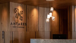 Ein Empfangsschalter mit einer Wandpaneele aus Holz und dem Logo des Hotels & der Residenz ANTARES.