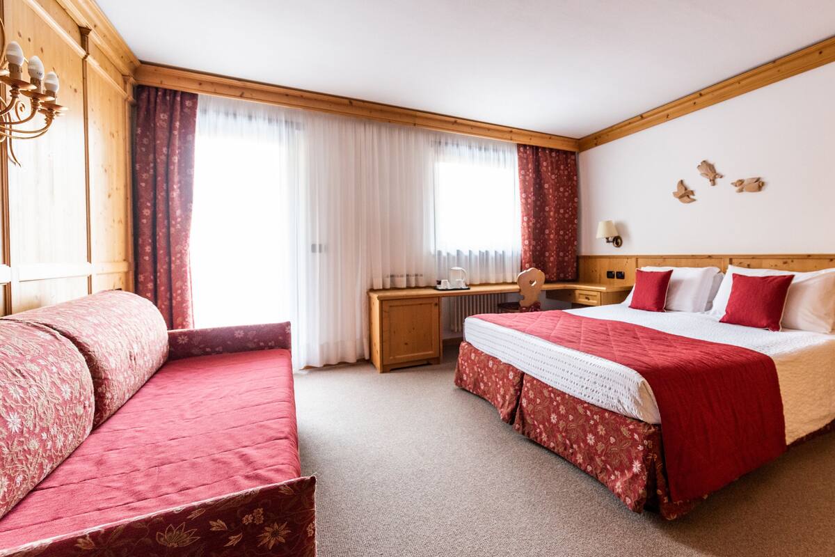 Habitación de hotel con una cama grande, un escritorio, una silla y una ventana con cortinas.