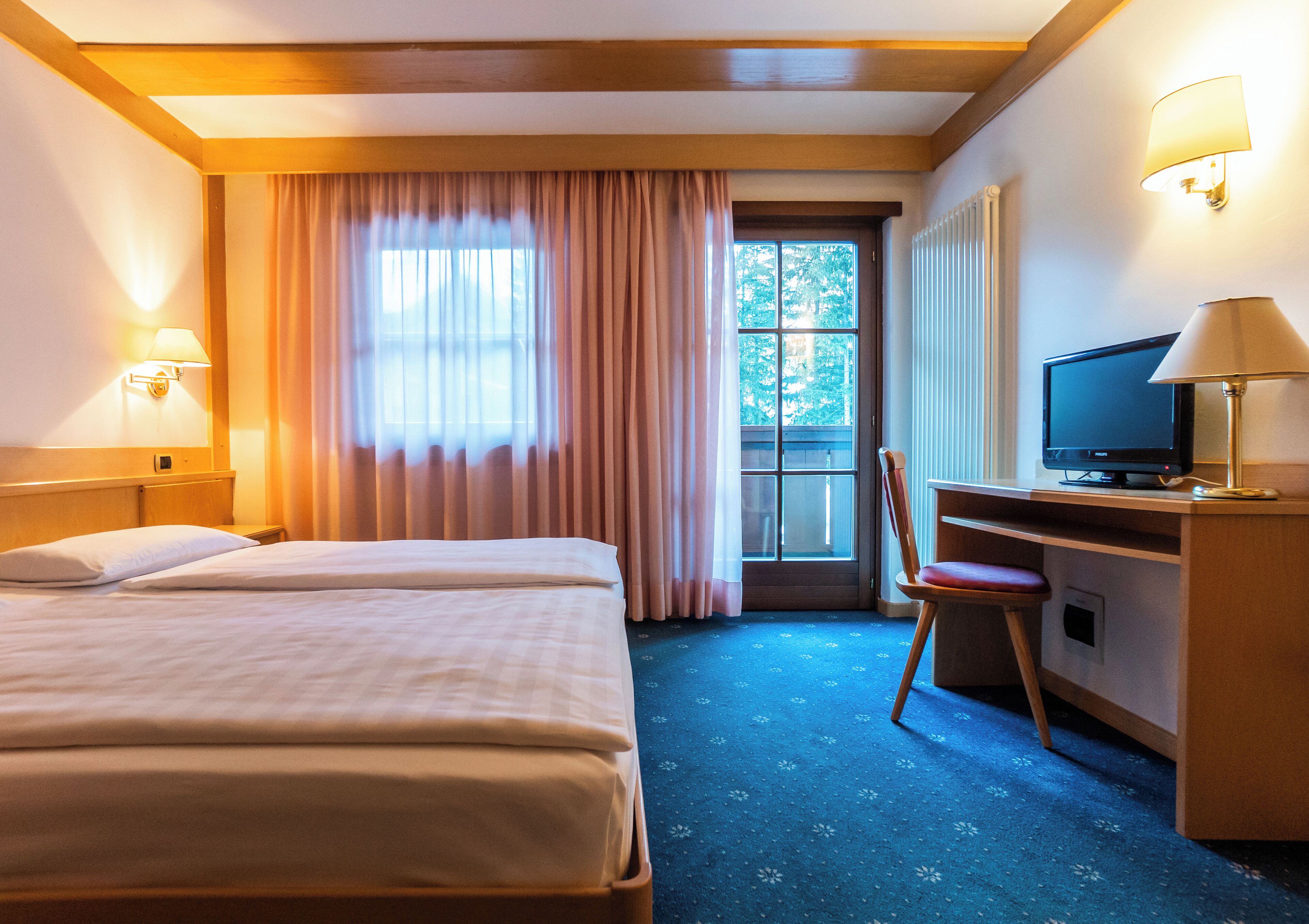 Una habitación de hotel con dos camas, un escritorio con televisor y una silla.