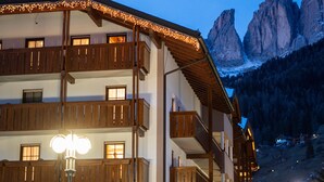 Un immeuble à plusieurs étages doté de balcons, avec une piste de ski et une vue sur les montagnes en arrière-plan.