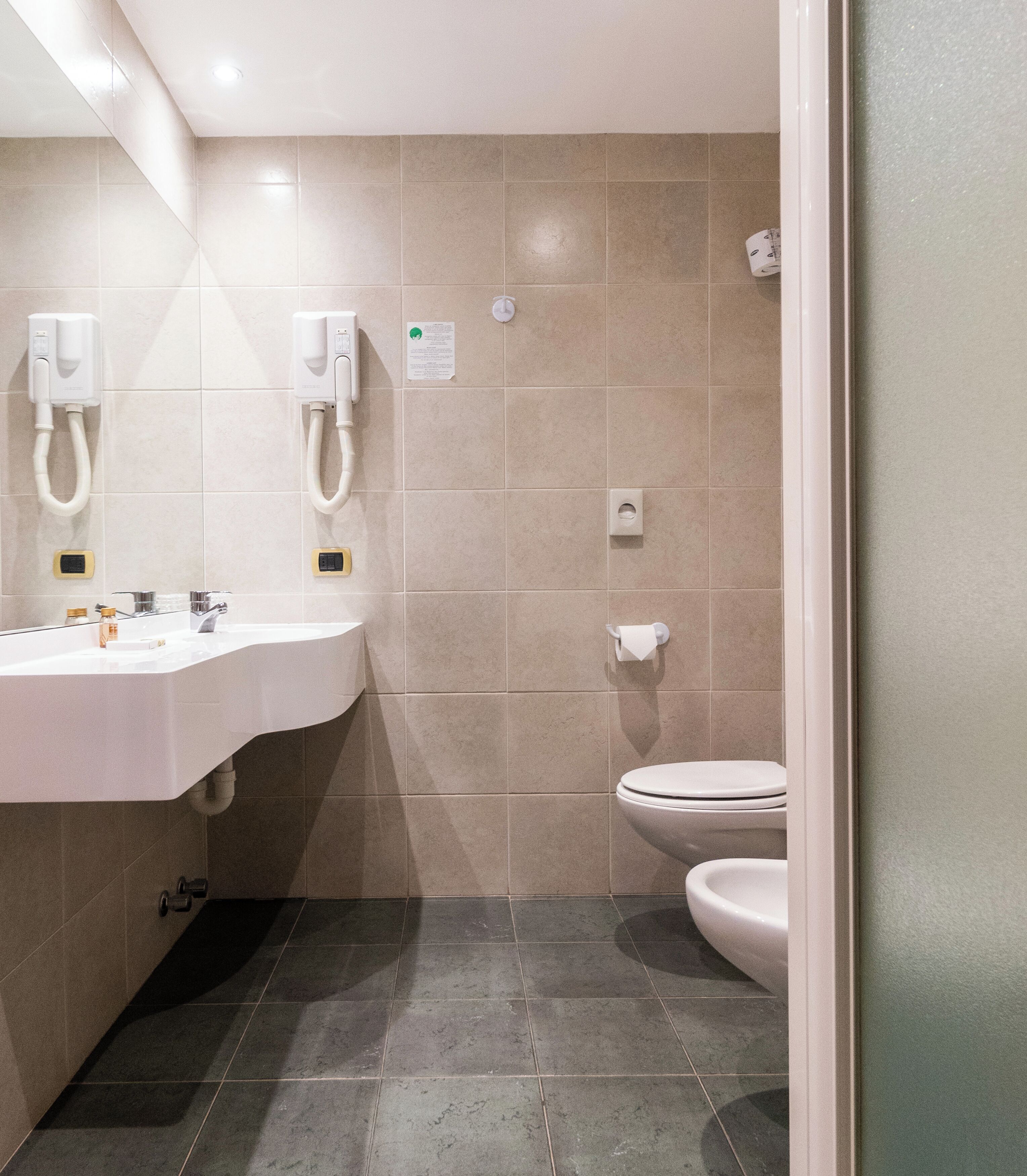 A modern bathroom with a white sink, a toilet, and a bidet.