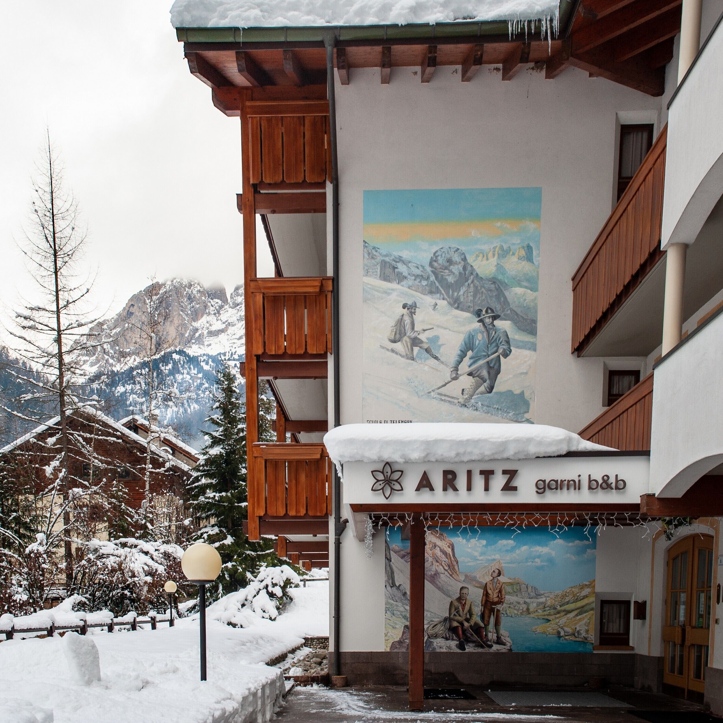 A hotel with a mountain view, wooden balconies, and a mural of a snowy landscape.